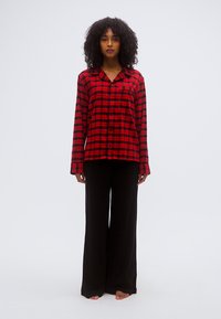 Κόκκινο και μαύρο καρό φανελένιο πυτζάμο με μακριά μανίκια και κουμπιά μπροστά, σετ με φαρδιά μαύρη πυτζάμα παντελόνι.