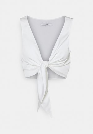 Crop top blanc en tissu lisse, avec un col en V et un détail de nouage à l'avant. Le tissu a un léger éclat et une coupe ajustée.