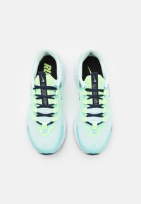 Baskets de course vert clair avec un dessus en maille, lacets navy et accents jaunes. Caractéristiques d'une semelle rembourrée et d'un design à bout arrondi.