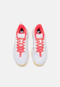 White athletic shoes with red accents, mesh upper, round toe, contrasting laces, and a textured rubber sole. Subtle branding on the tongue.