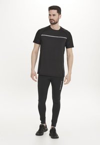 Sort atletisk t-shirt og leggings, med fugttransporterende stof, korte ærmer og reflekterende accenter på brystet og benet.