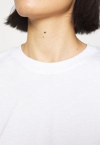 Witte katoenen t-shirt met een ronde hals en korte mouwen. De stof lijkt zacht met een gladde textuur. Geen zichtbare patronen of accenten.