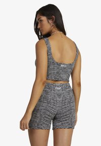 Black and white striped crop top and shorts set, featuring a ribbed texture and logo accents on the back of both pieces.