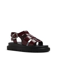 Maroon glossy leather sandals with cut-out design, adjustable ankle strap, and black rubber sole featuring ridged texture.