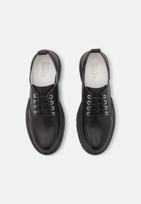 Chaussures en cuir noir au toucher lisse, avec des œillets en aluminium et des lacets noirs. Bout arrondi et semelle en caoutchouc noir durable.