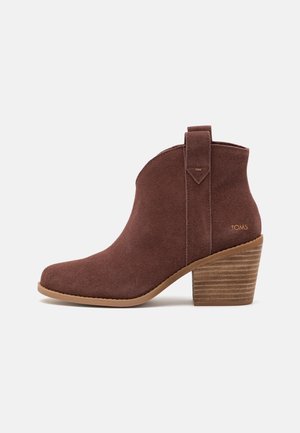 Bruine suède enkellaars met een puntige neus, een gestructureerd zijpaneel en een gestapelde hak. Voorzien van een lus aan de achterkant voor gemakkelijk aantrekken.