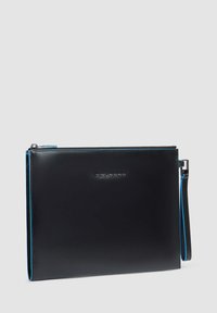 Cartera de piel negra con costuras azuladas y cierre de cremallera. Cuenta con una correa para la muñeca y un logo en relieve en la parte frontal.