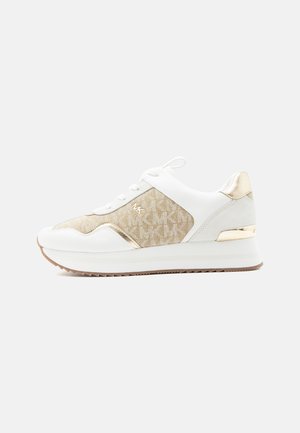 Witte en beige sneaker met gouden accenten, zijpanelen van stof met logopatroon, vetersluiting en een dikke zool met een gestructureerd loopvlak.