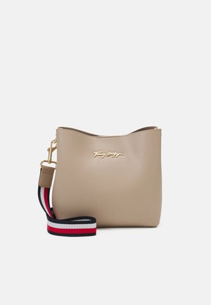 Beige Leder-Umhängetasche mit goldener Logo-Plakette und abnehmbarem Riemen mit rot-weißen und marineblauen Streifen.