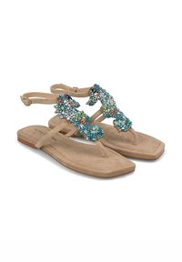 Sandalias de gamuza color marrón claro con suelas planas, que cuentan con una correa decorativa adornada con cristales de colores en patrones florales. Correas ajustables en los tobillos.