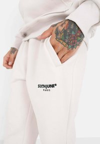 Lichtbeige sweatpants met een zachte textuur, voorzien van een zwart "SIXTHJUNE PARIS" logo op de linkerzak en zijzakken.