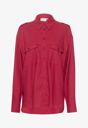 Punane nööpidega särk krae, kahe rinna tasku, õlavarre epauletid ja pika varrukaga, valmistatud siledast ja kergest kangast.