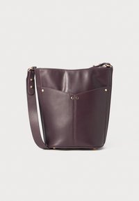 Bolso tipo cubo de cuero burdeos con correa ajustable, que cuenta con dos bolsillos frontales y herrajes en tono dorado. Textura suave, forma estructurada.