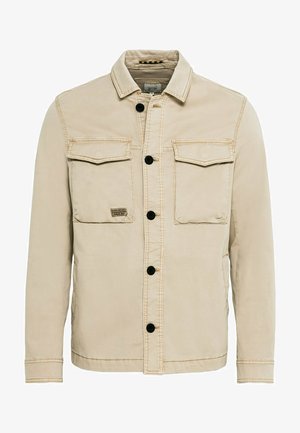 Beige jakke lavet af bomuld med krave, knaplukning, to brystlommer og synlige stikninger.