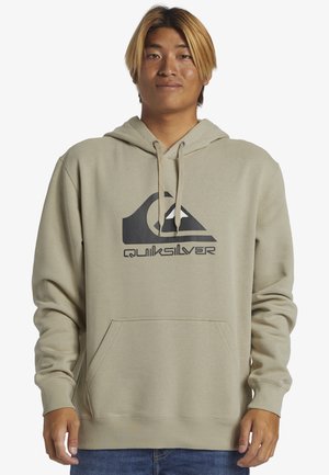 Lysbeige hættetrøje med en front kangaroo-lomme, snoretræk i hætten og et stort sort Quiksilver-logo på brystet. Blød stoftekstur.