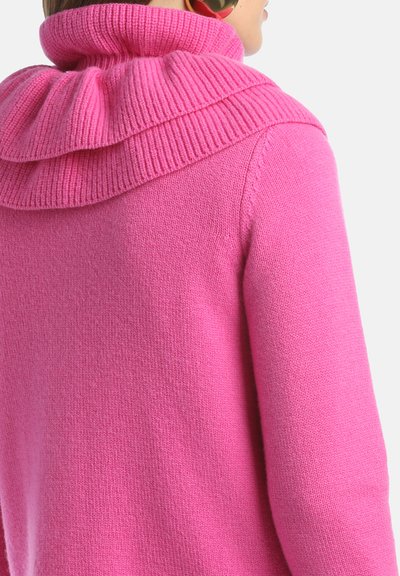 Suéter fucsia con un cuello de cowl grueso y acanalado, que presenta una textura suave y una silueta ajustada, visto desde la parte posterior en un modelo.