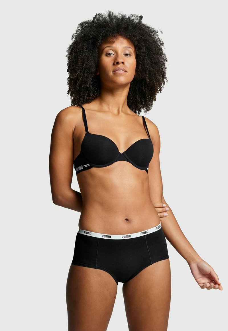 Schwarzer kabelloser BH mit geformten Cups und dünnen Trägern, kombiniert mit schwarzen Hipster-Unterhosen mit einem weißen Puma-Logo-Bund.