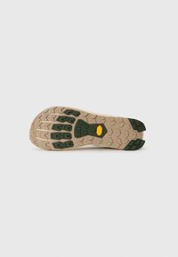 Semelle en caoutchouc beige avec un motif de bande de roulement vert et un logo jaune au centre. Dispose de rainures profondes pour une meilleure traction.