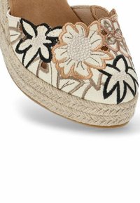 Alpargatas de tela blanca con bordado floral en beige y negro. Presentan una suela de yute y un forro interior suave.
