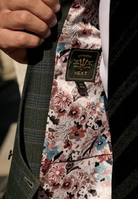 Dunkelgrüner kariert Blazer mit einem floralem Satinfutter in rosa, blau und braun mit einem "NEXT"-Label. Weiche Textur, taillierte Passform.