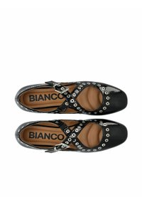 Zapatos negros de charol con cortes, correas cruzadas y acentos de ojales plateados. Presentan una puntera redondeada y una plantilla acolchada.