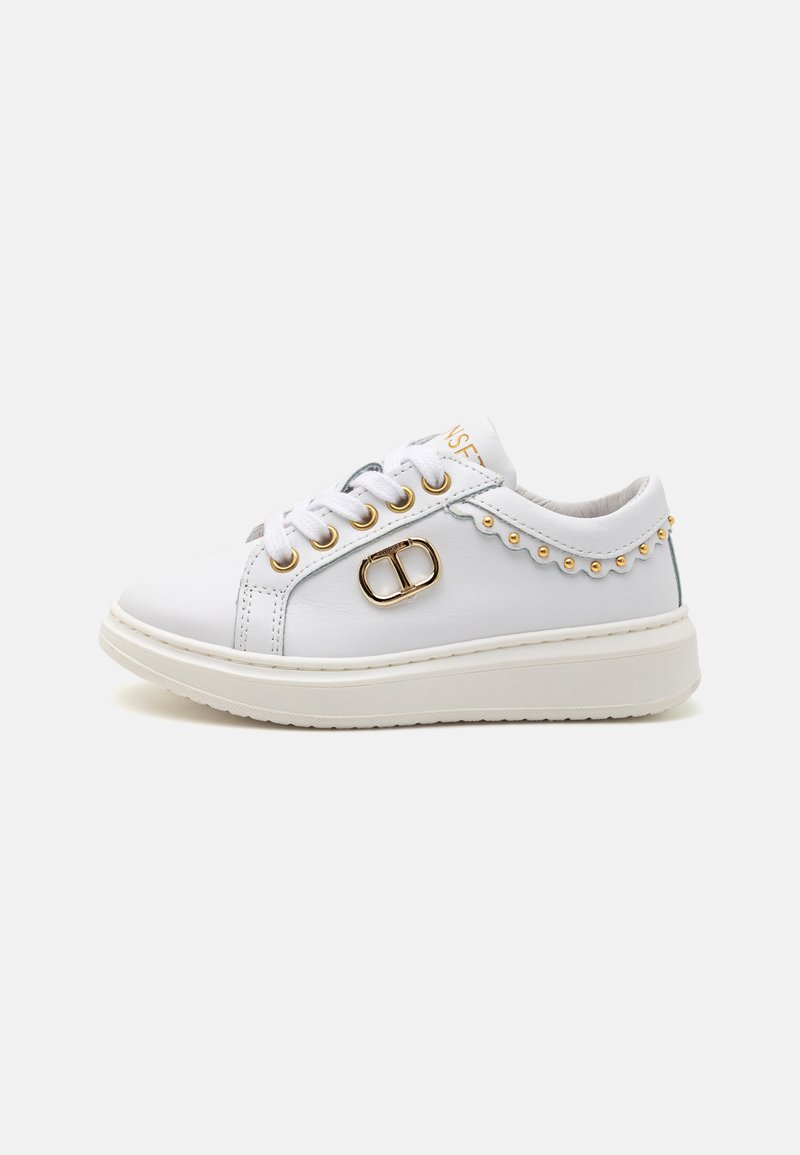 Sneakers bianchi con finitura in pelle liscia, passanti dorati e perline decorative lungo il lato. Caratterizzano una suola bianca spessa e una punta arrotondata.