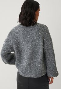 Grauer Strickpullover mit strukturierter Oberfläche, verziert mit verstreuten Pailletten, mit überschnittenen Schultern und abgerundetem Saum.