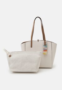 Sac fourre-tout couleur crème avec des poignées marron et une étiquette multicolore, accompagné d'une petite pochette en tissu crème avec une anse en boucle.