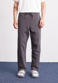 Graue Sweatpants mit einem elastischen Bund und Kordelzug, ausgestattet mit Seitentaschen und einer weichen, glatten Textur. Lässige Passform, die für Komfort sorgt.