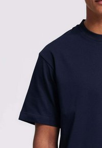 Marineblauwe katoenen T-shirt met een ronde hals, korte mouwen en een gladde, gelijkmatige textuur, zonder zichtbare patronen of accenten.