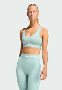 Light teal sports bra and high-waisted leggings in a smooth, stretchy material with white accent branding. Simple, streamlined design.
