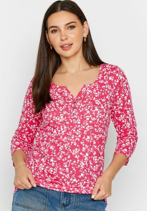 Camicia a maniche lunghe rosa floreale con scollatura a barca, patta dei bottoni e motivi di fiori bianchi; realizzata in tessuto leggero e testurizzato.