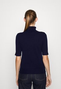 Tmavě modrý svetr s krátkým rukávem a rolákem, s přiléhavým střihem, žebrovanou texturou na límečku a lemu a hladkým materiálem.