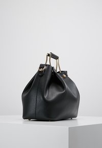 Sort læderhandtaske med en blød form, der har en tekstureret overflade, guldfarvet hardware og et design med dobbelt håndtag. Rundet bund.