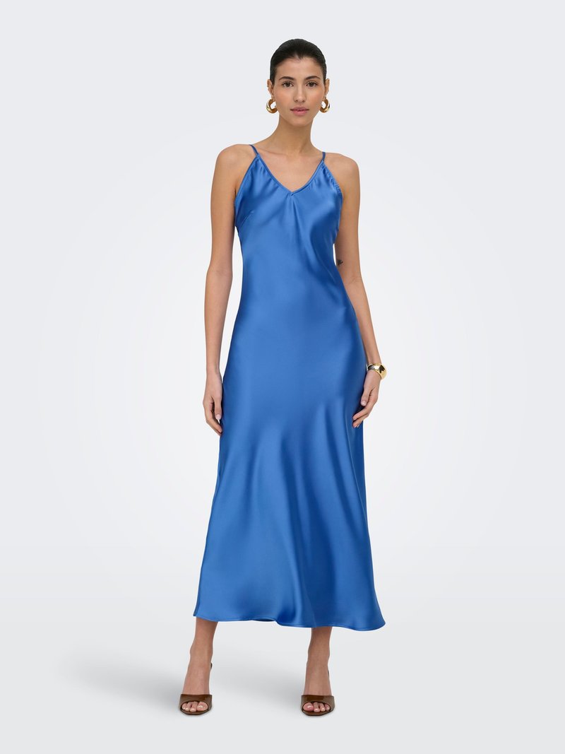 Femme portant une robe midi en satin bleu sans manches avec fines bretelles, des boucles d'oreilles anneaux dorées, une montre-bracelet en or et des talons ouverts marron.