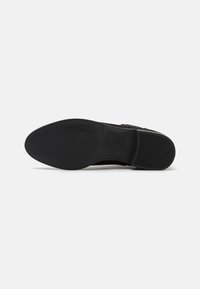 Black shoe sole with textured grip pattern, featuring rounded toe and a smooth finish. Construction material appears rubber with flex grooves.
