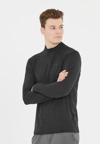 Sort langærmet zip-up skjorte lavet af et glat stof, med en høj krave og minimal design uden synlige logoer eller mønstre.