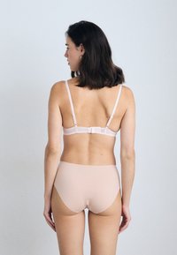 Roze lingerie set met een bh met verstelbare straps en haaksluiting, gecombineerd met soepele high-waisted slipjes, beide in zachte stof.