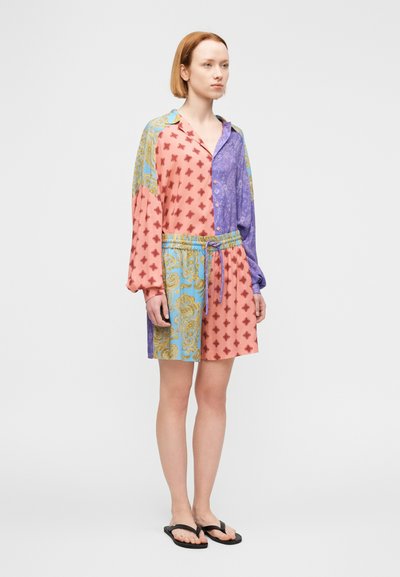 Krátke šaty-košeľa s viacerými farbami, s rôznymi vzormi vo farbách ružovej, modrej, fialovej a žltej. Súčasťou je šnúrka v páse a gombíky.