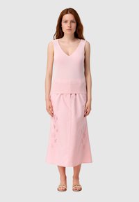 Top senza maniche di un rosa chiaro con scollatura a V, abbinato a una lunga gonna coordinata con delicati ricami floreali e una texture morbida.