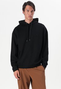 Felpa nera con cappuccio regolabile, vestibilità rilassata, orlo elastico e un logo discreto sul petto. Tessuto in misto cotone con una superficie liscia.