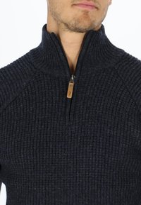 Dark navy half-zip sweater with ribbed texture, stand-up collar, and leather zip pull accent. Tight-fitting design with raglan sleeves.