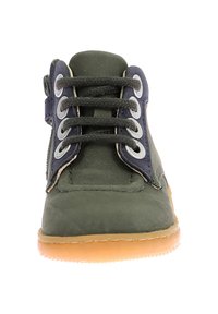 Zapato de lona verde con detalles en azul marino, puntera redonda, diseño de cordones y suela de goma. Presenta ojales metálicos y una cremallera lateral para un fácil uso.