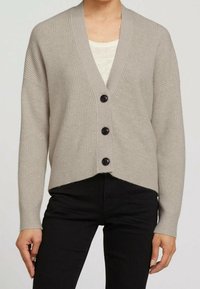 Cardigan tejido de color gris claro con cuello en V, hombros caídos y botones negros. Presenta una textura acanalada y un dobladillo recortado y ligeramente asimétrico.
