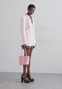 Ljust rosa oversized kavaj, brun veckad kjol, rosa handväska med mönster, och kraftiga svarta plattformsskor med vristrem.