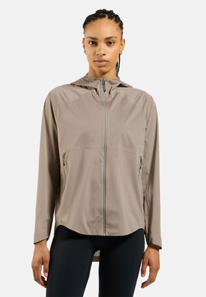 Lightweight, beige zip-up jacket with a hood, featuring side pockets, a smooth texture, and a logo accent on the chest.