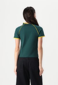 Grønn polo skjorte med gule detaljer, korte ermer og en tettsittende design. Visningen viser baksiden, som fremhever fargen og søm detaljene.