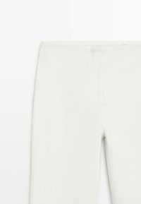 White fitted pants with a smooth waistband and hidden front closure on a plain white background.