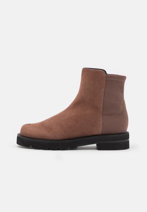 Bottine cheville en suède marron avec une finition lisse, panneau latéral en élastique, bout rond et semelle en caoutchouc noir texturé.
