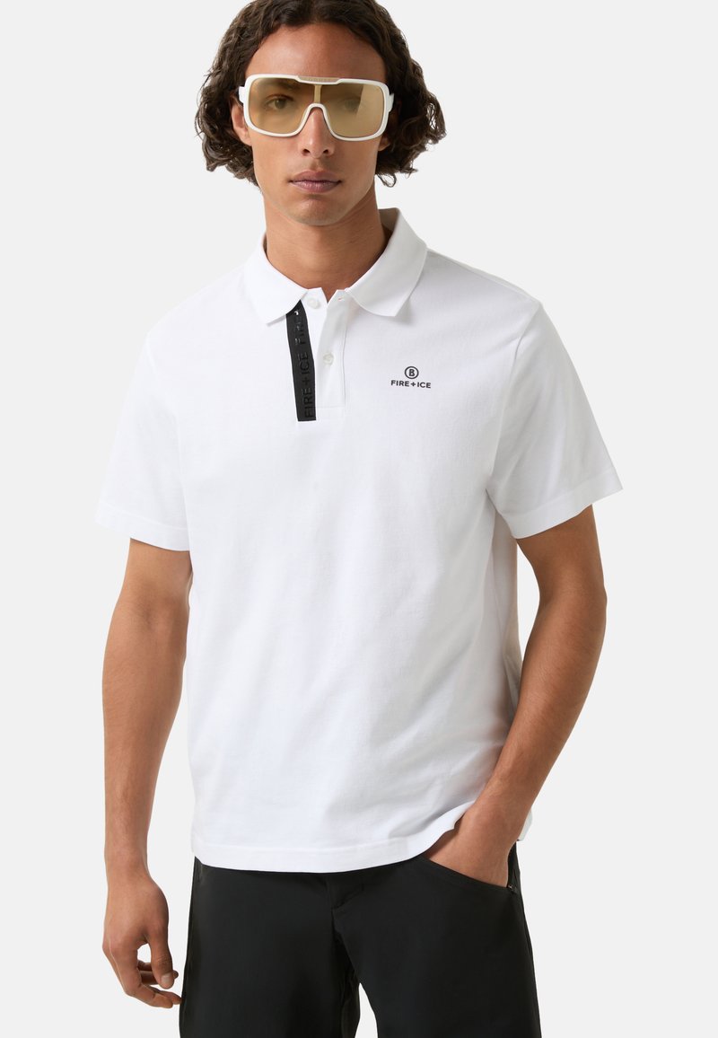 White polo shirt featuring a black two-button placket with logo and black accents, made of textured fabric, paired with dark shorts.
